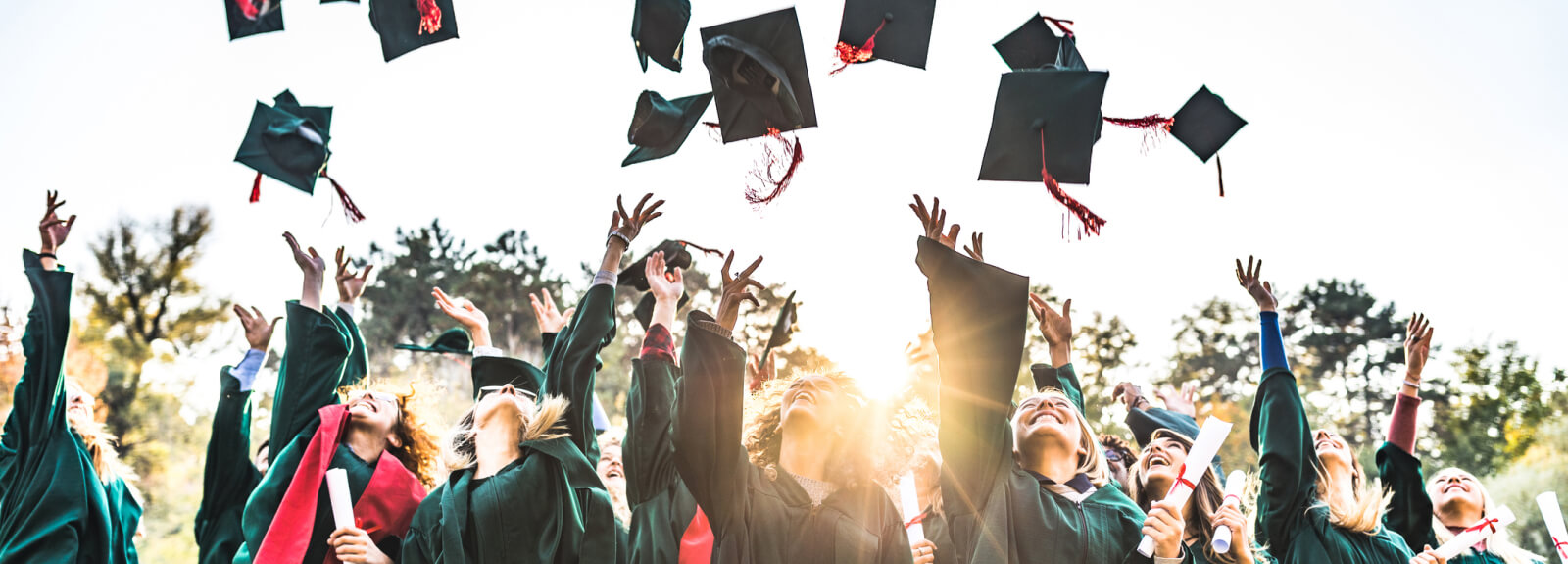 Multiple students throwing graduation caps in the air