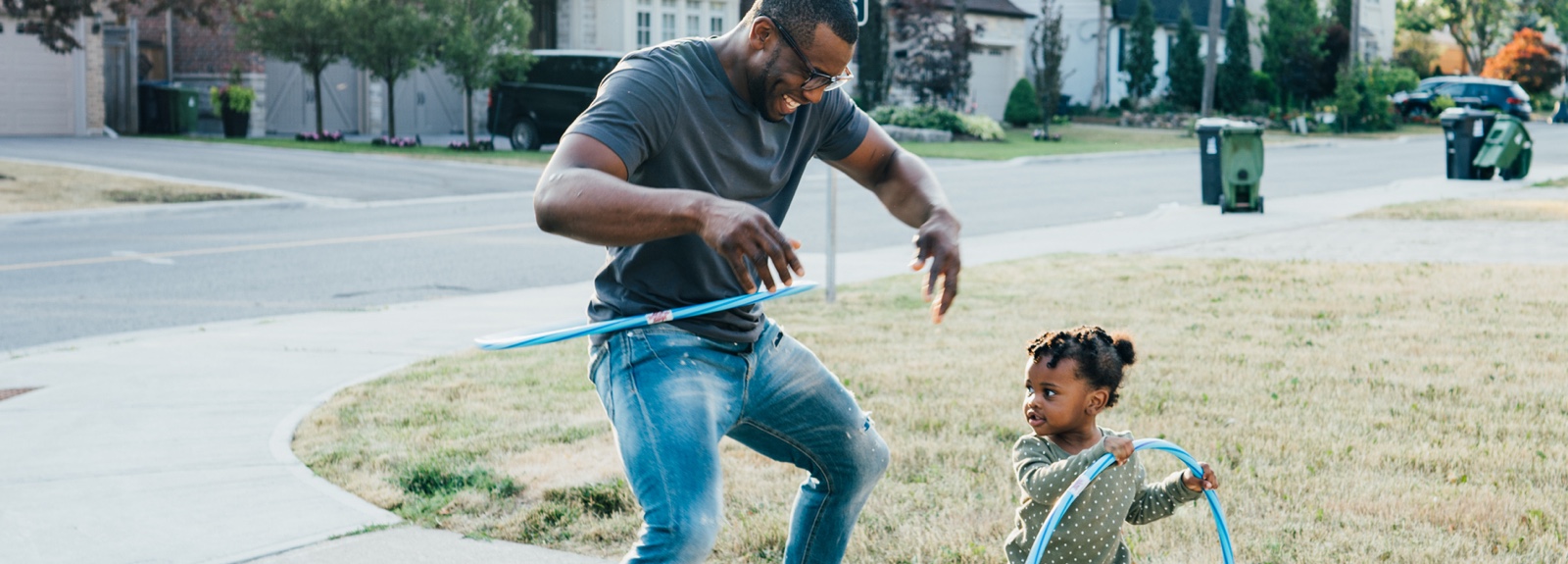A dad hula hooping with a toddler.