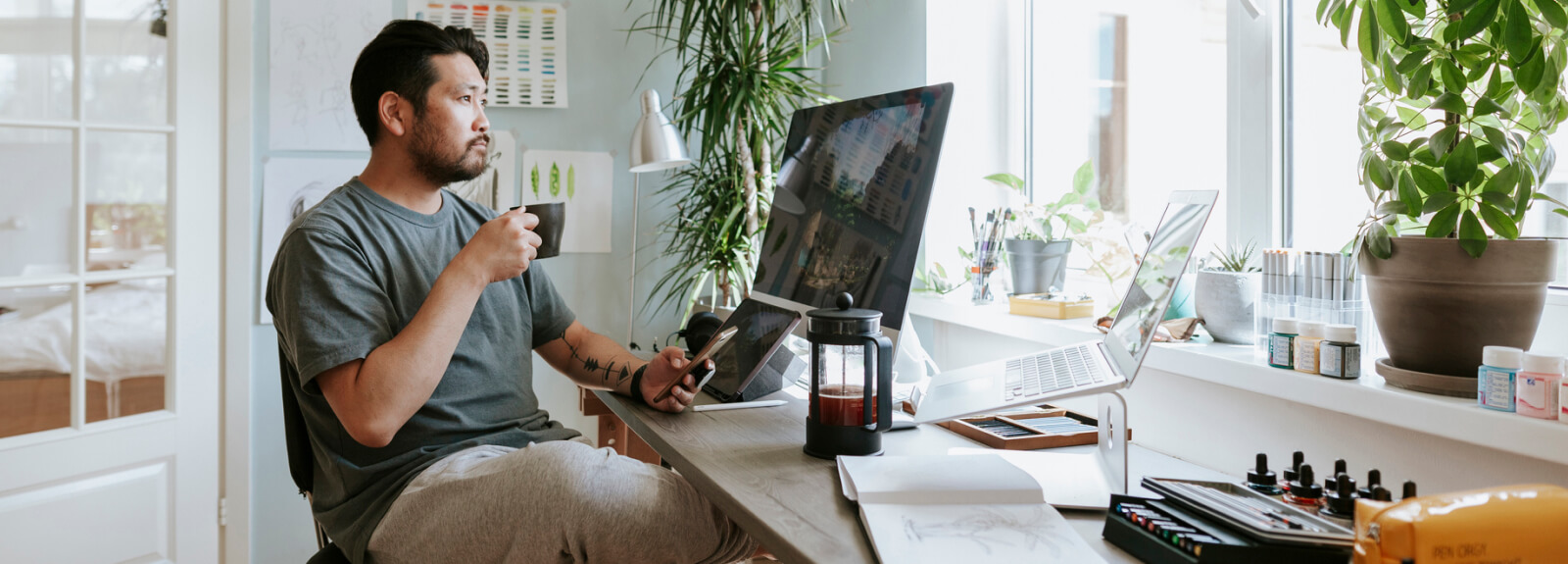Man sitting at a computer holding a coffee mug