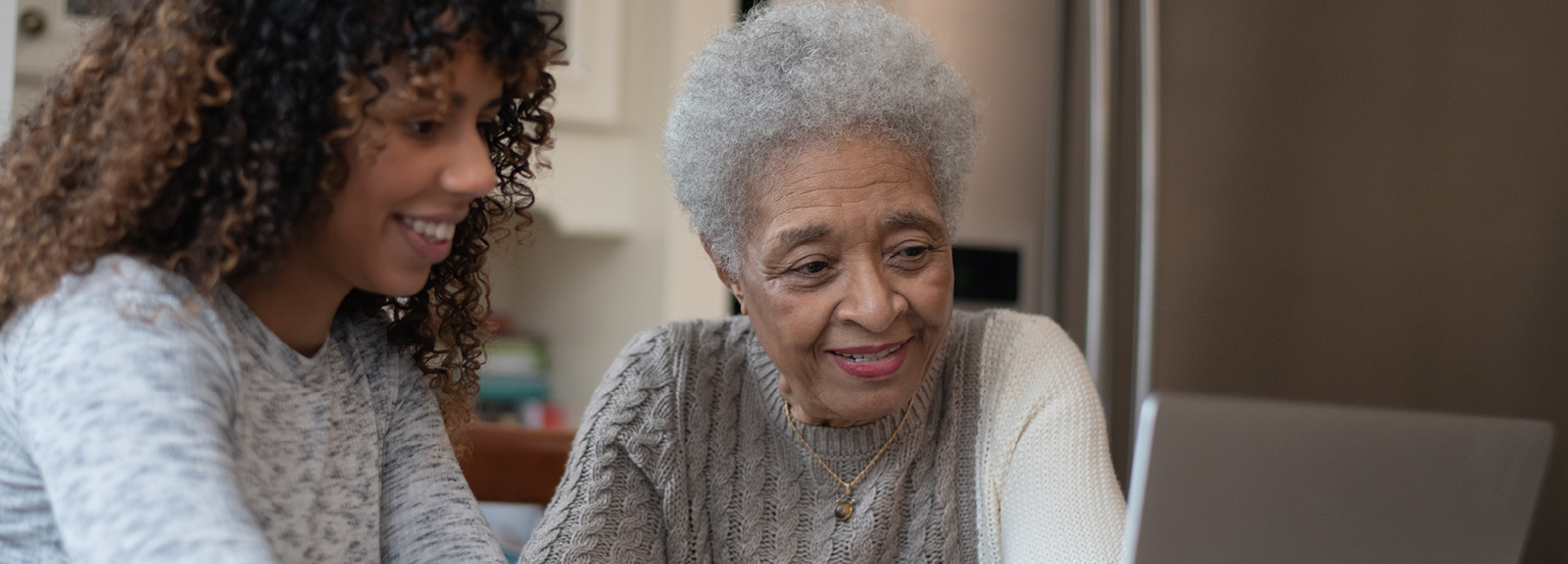 Woman assists elderly relative with her computer.