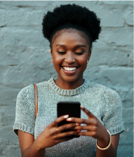 A young woman smiling and holding a smartphone