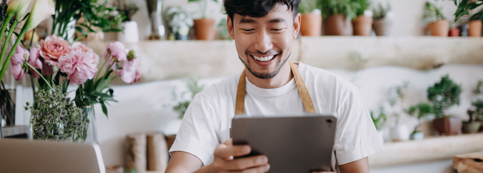 A man in a flower shop holding a tablet