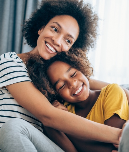 A mother and young child holding each other on a couch.